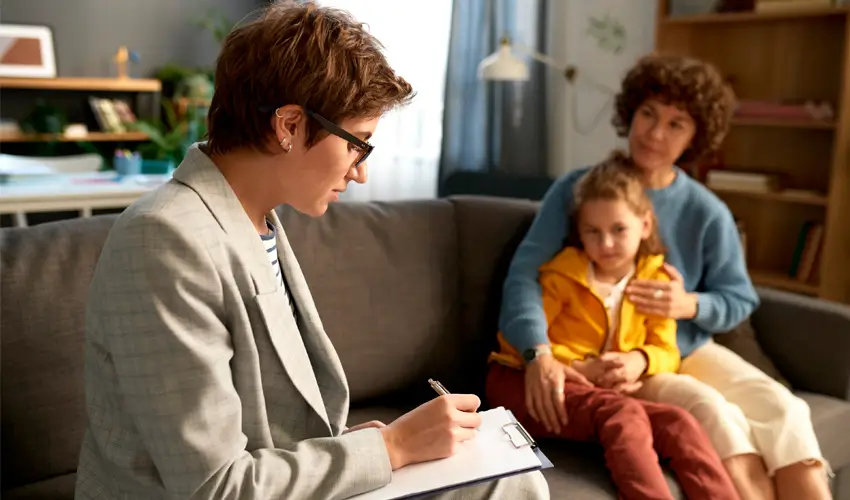 Una trabajadora social realizando su trabajo frente a una mujer y su hija. Foto extraída de iStockphoto y utilizada por Iplacex.